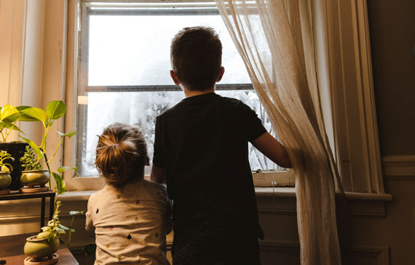 Dos niños mirando por la ventana, simbolizando el futuro y el crecimiento en su nuevo hogar familiar en Pobla de Farnals