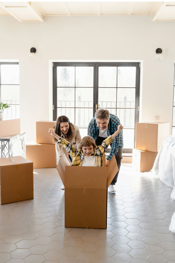 Pareja joven con su hijo sentada en el suelo con cajas de mudanza, representando la compra de un nuevo hogar en Valencia